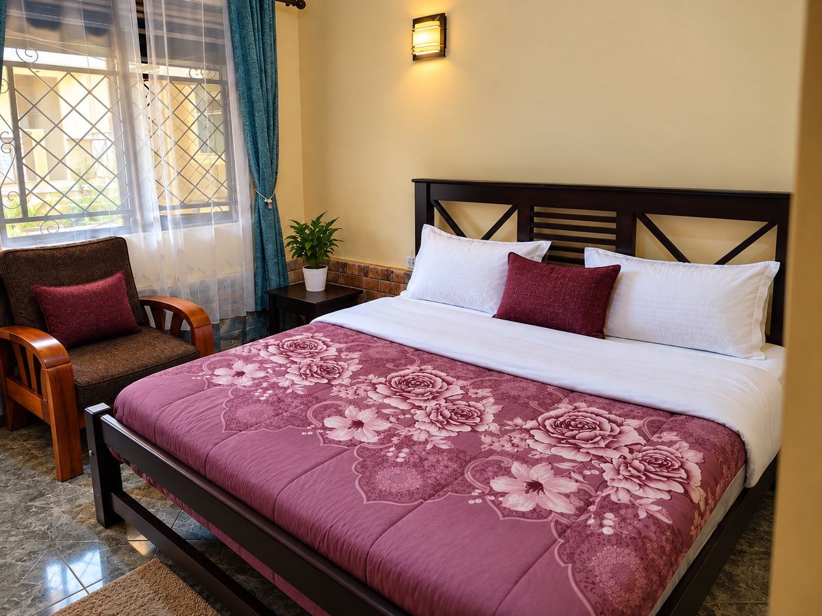 Standard room at The Cosy Inn Kiwenda with a king bed, armchair and garden-facing window