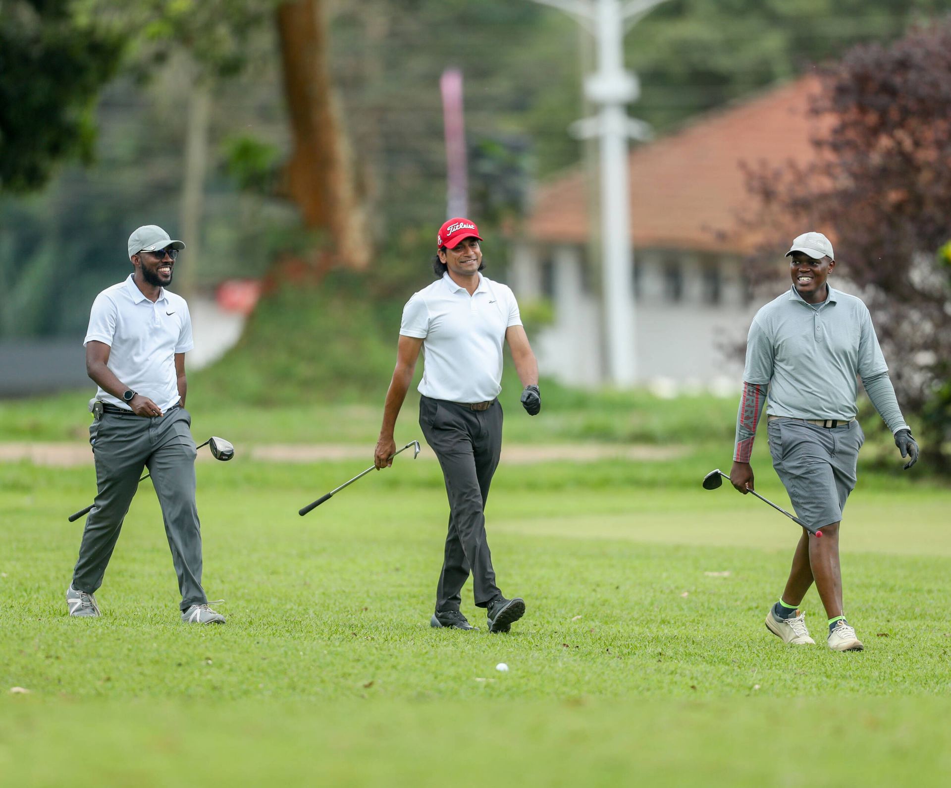Three golfers walking the fairway at the Mary Louise Simkins Memorial Golf Club, Namulonge