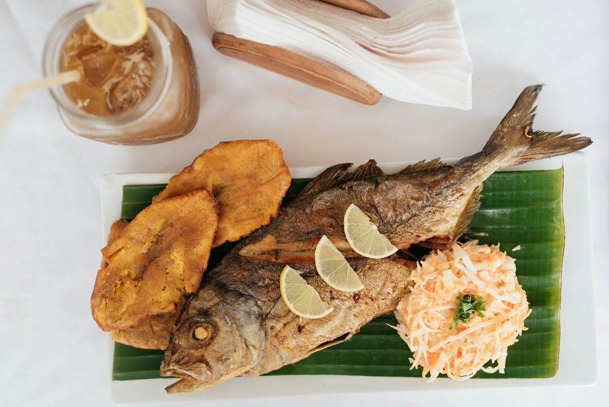 Whole fried fish served with fried plantain and fresh salad